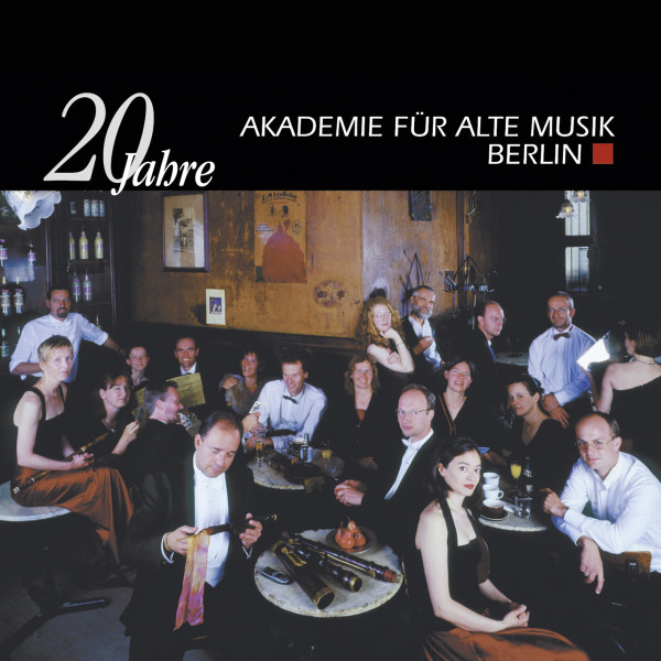 Ein Foto der Musiker:innen mit ihren Instrumenten, die an Bistro-Tischen sitzen und in die Kamera schauen. Oben drüber ist das Logo und 20 Jahre zu sehen.