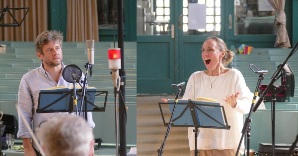 Ein Mann und eine Frau singen hinter Notenständern und Mikrofonen