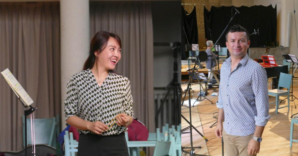 Ein Mann und eine Frau stehen in einem Raum voller Stühlen und Mikrofonen