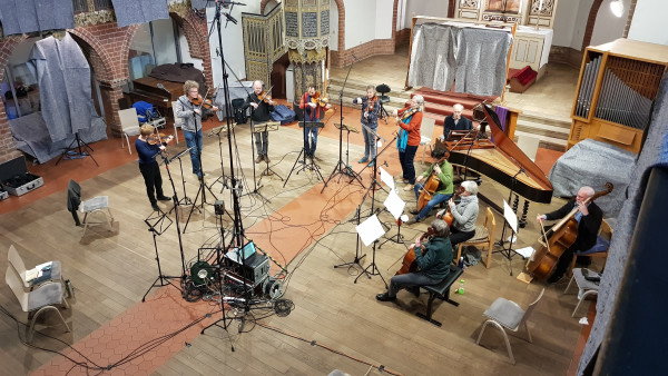 Fotografie von Musikerinnen die inmitten von Mikrofonen musizieren